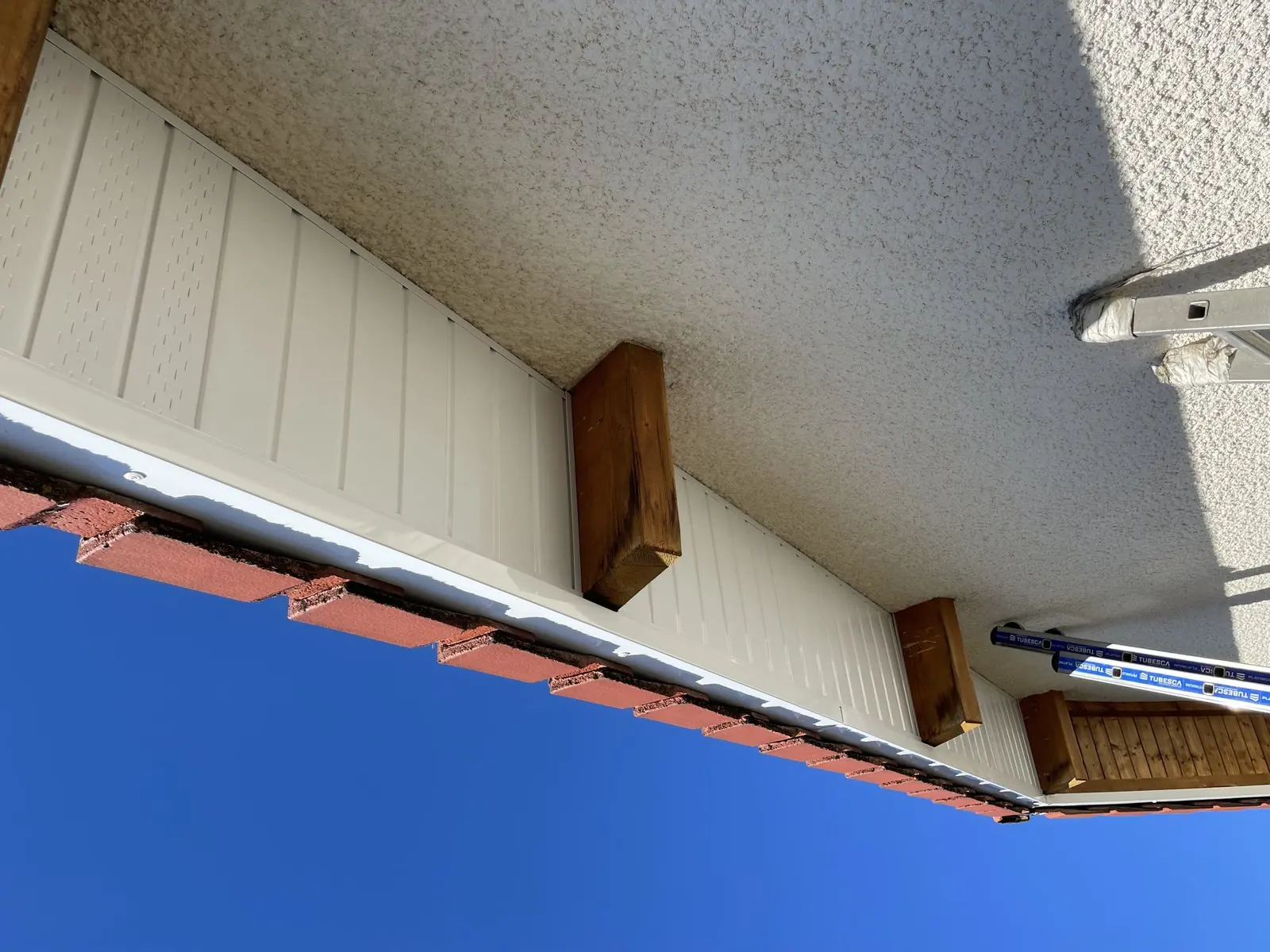 Sous-face de toit habillée en PVC blanc et chevrons en bois, chantier Catenacci