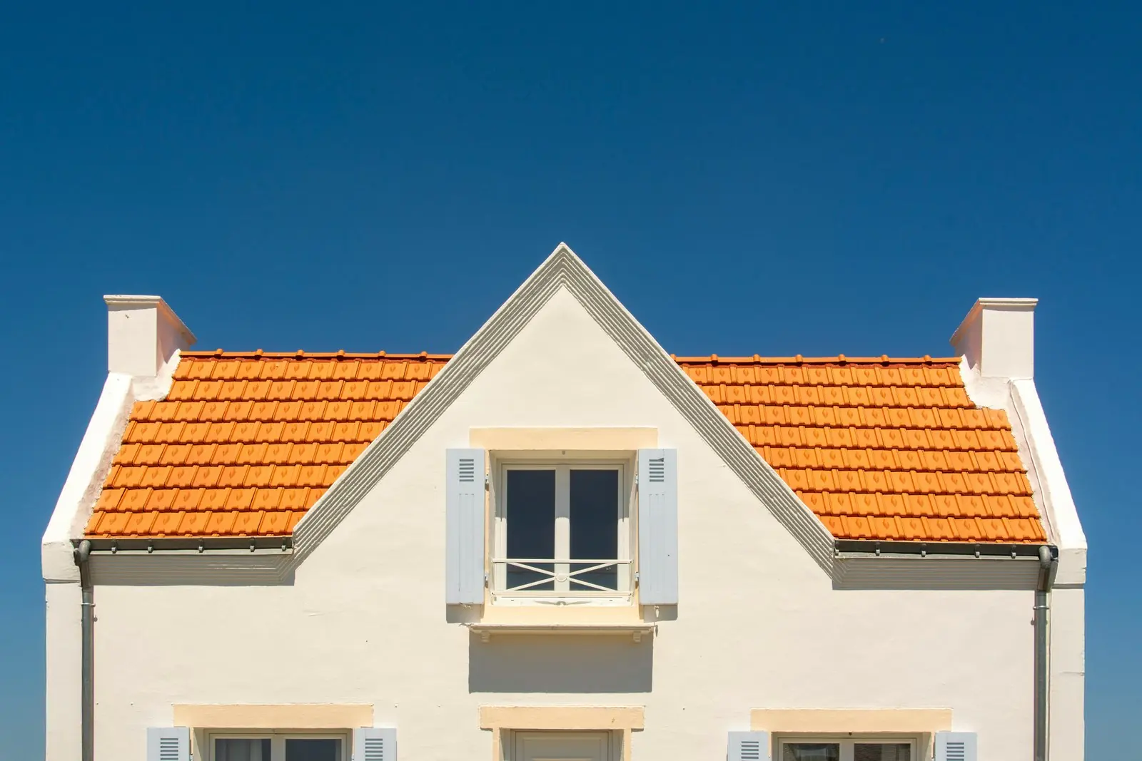 Pignon d’une maison et sa toiture en tuiles orange